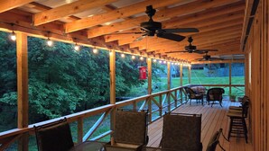 A covered outdoor deck with wooden beams, string lights, and outdoor furniture. - Family lake escape! Huge deck/BBQ/fire pit. Bunk room. 5 min to boat ramp! Pets! (Cadiz)