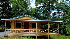 A wooden cabin with a porch, surrounded by greenery. - Family lake escape! Huge deck/BBQ/fire pit. Bunk room. 5 min to boat ramp! Pets! (Cadiz)