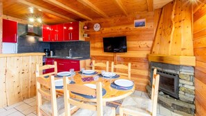 A wooden cabin interior with a dining area, red cabinets, a fireplace, and a television on the wall. - L'oree DU Bois - Arole (VAL CENIS)
