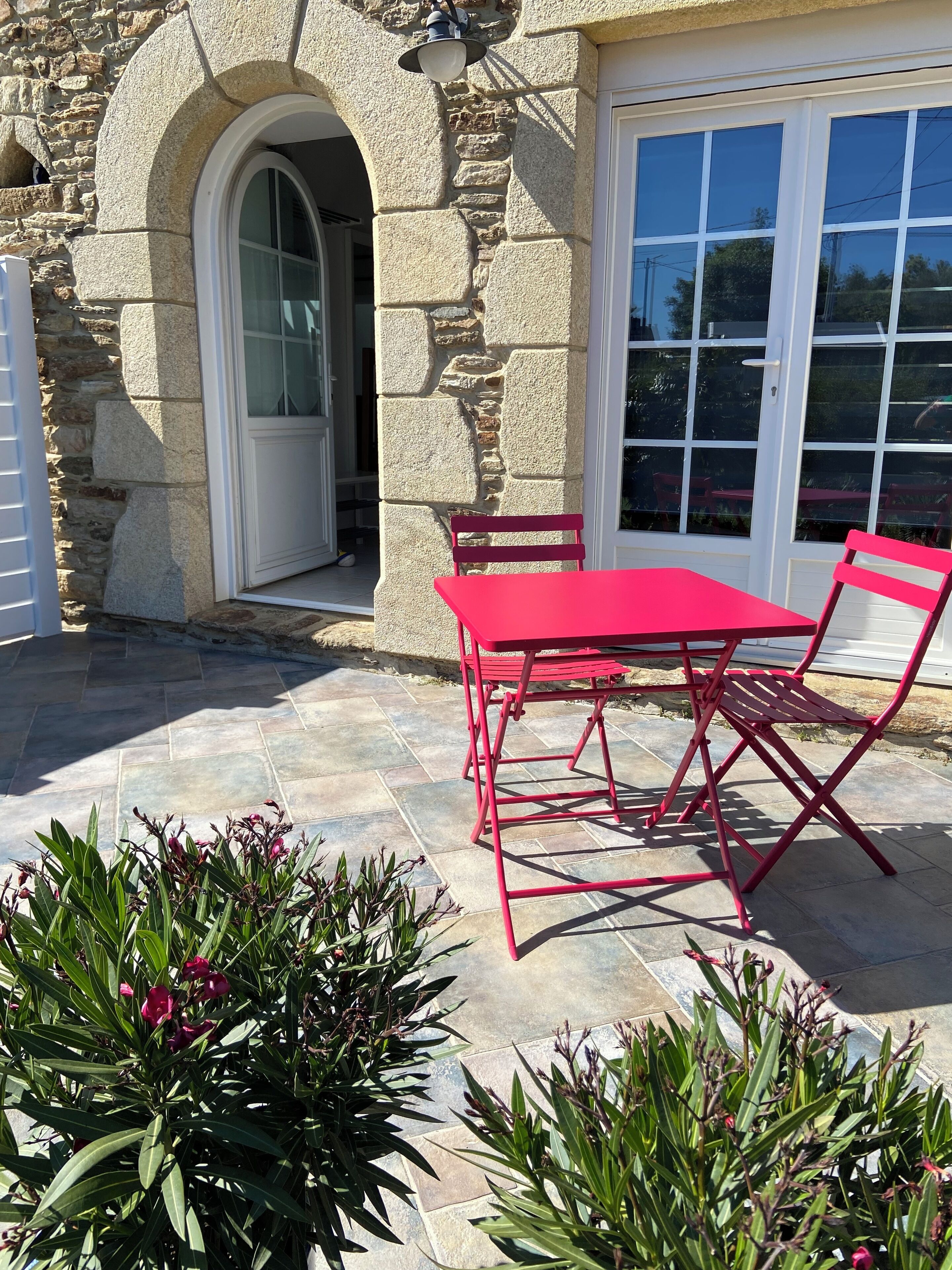 A stone building with a red table and chairs outside.