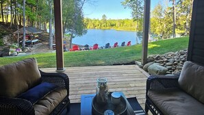 Un patio al aire libre con mobiliario de mimbre y vistas a un lago.