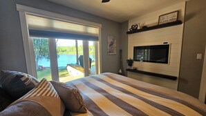 Un dormitorio con una cama grande, televisor y vista a un lago.