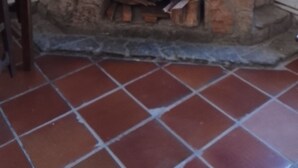 A stone fireplace with a wooden mantel, a chair to the left, and a tiled floor. - Eco Art Hotel (Peralejos de las Truchas)