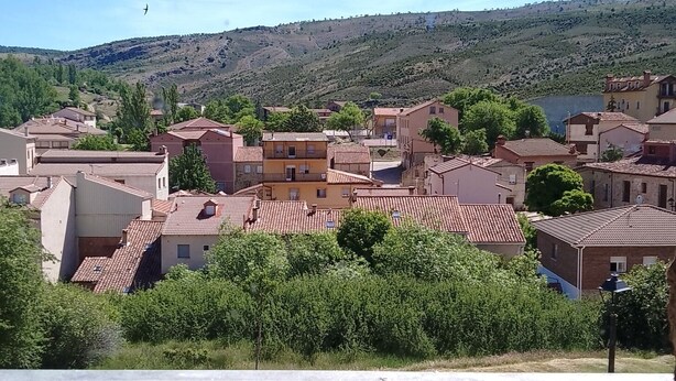 A residential area with terracotta-roofed houses, a clear sky, and a hilly landscape in the background. - Eco Art Hotel (Peralejos de las Truchas)