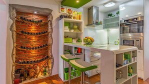 A kitchen with a brick wall, modern appliances, and green bar stools. - 1 bedroom cozy apartment in Pula (Pula)