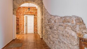 A hallway with a stone wall, a tiled floor, and a white door. - 1 bedroom cozy apartment in Pula (Pula)