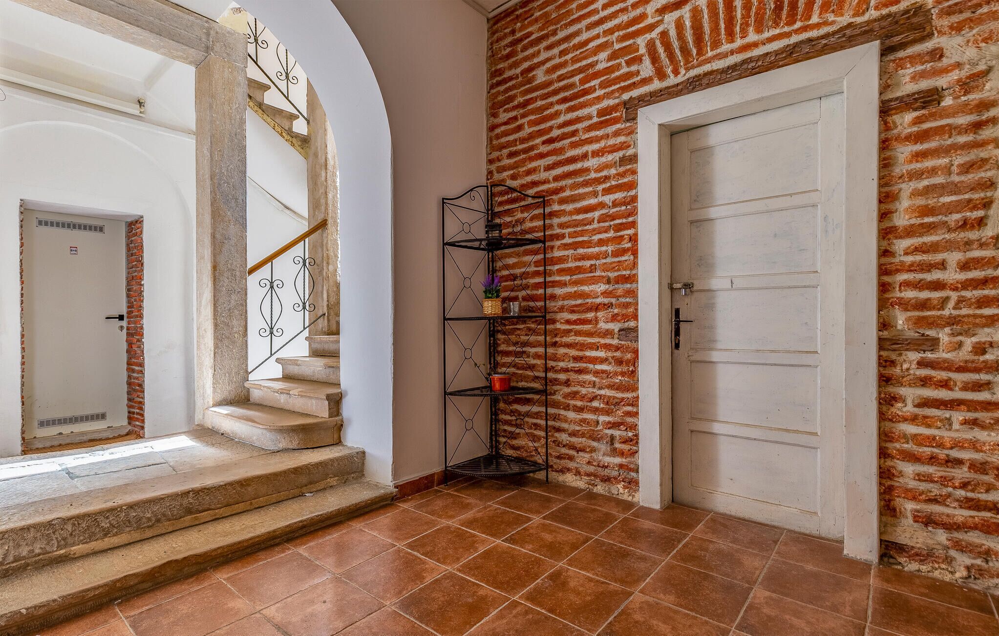 Una escalera que lleva a una habitación con un muro de ladrillo y una puerta blanca.