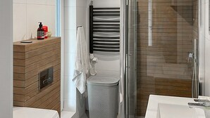 A modern bathroom with a wooden vanity, a shower with a glass door, and a toilet with a perforated waste basket. - Gorgeous home in Drogoradz (Drogoradz)