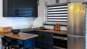 A modern kitchen with dark cabinets, a stainless steel refrigerator, a wooden countertop, and a window with blinds. - Gorgeous home in Drogoradz (Drogoradz)