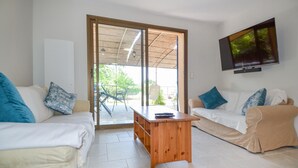 A living room with two white sofas, a wooden coffee table, and a TV mounted on the wall.