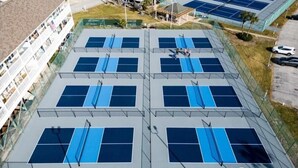 An outdoor tennis court complex with multiple courts, surrounded by a fence, and adjacent to a building with balconies. - 2/2, Sleeps 6, 9 hole golf course on site, pool out your front door, 8 min.beach (Destin)