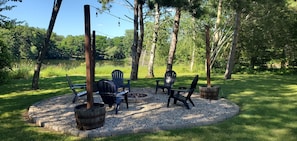 A circular seating area with chairs and a fire pit, surrounded by a gravel border and trees. - Peaceful retreat on Fawn Lake, local Winery, & minutes from the Dells! (Wisconsin Dells)
