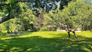 Um parque com gramado, árvores e um coreto.