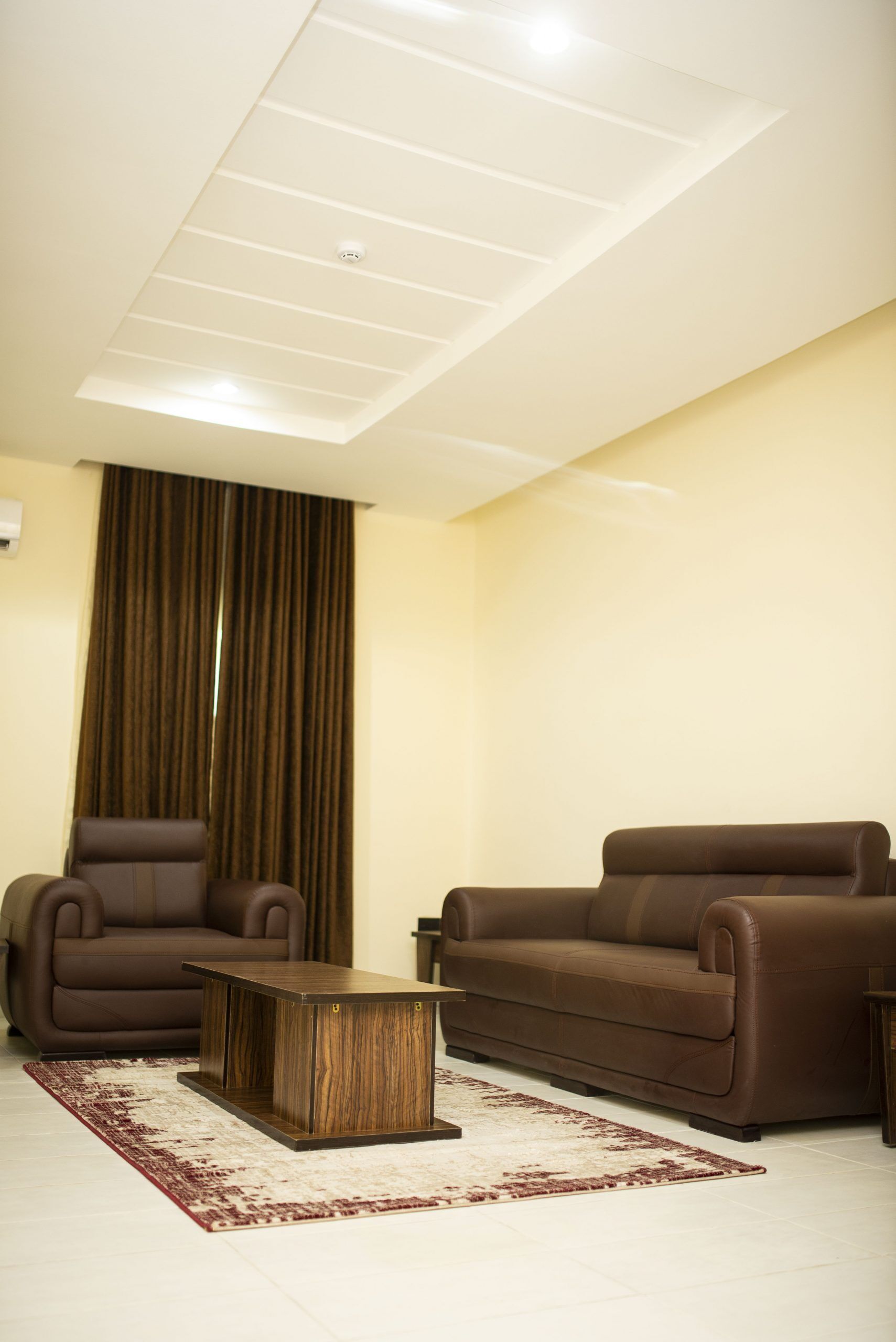 Una sala de estar con un sofá marrón, un sillón marrón y una mesa de centro de madera.
