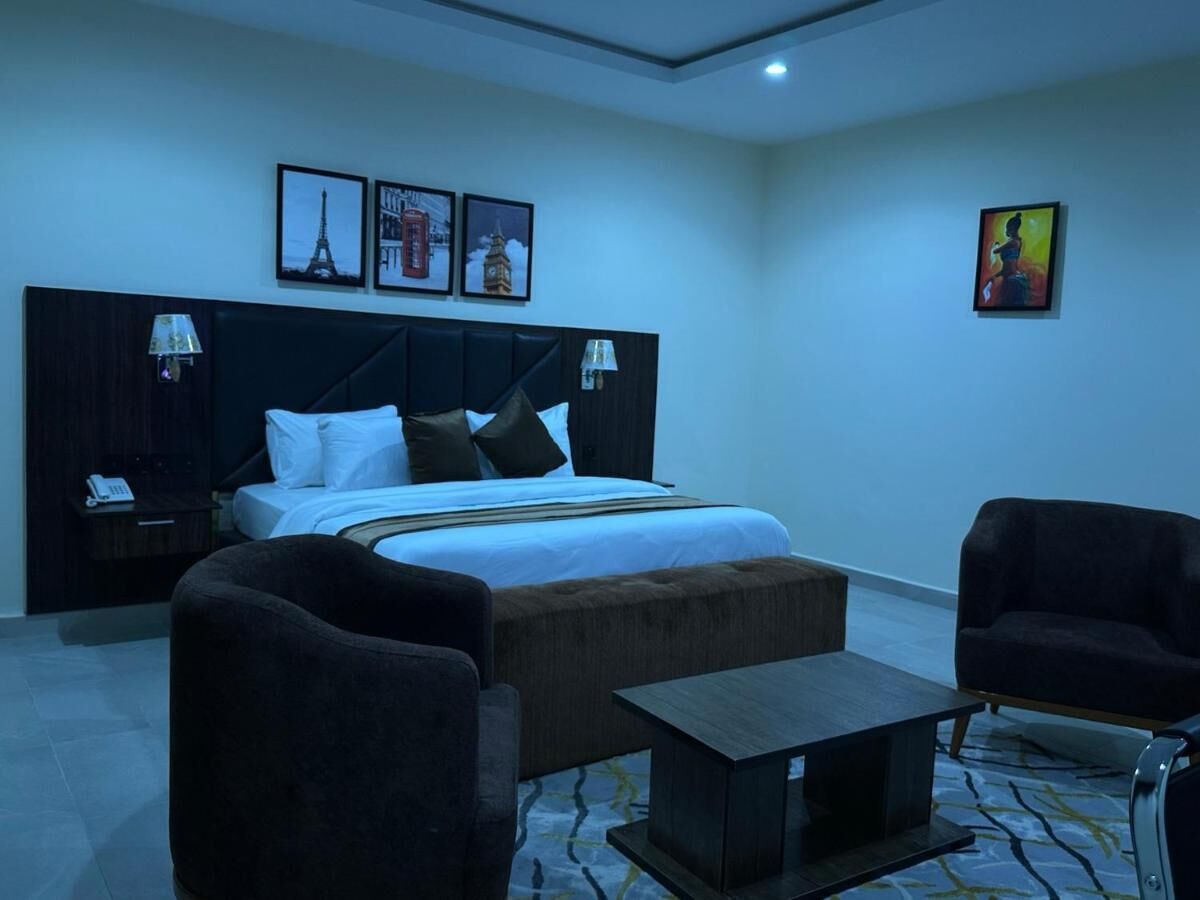 Une chambre d’hôtel moderne, dotée d’un grand lit, de deux tables de chevet, d’un canapé, d’une petite table et d’œuvres d’art accrochées aux murs.