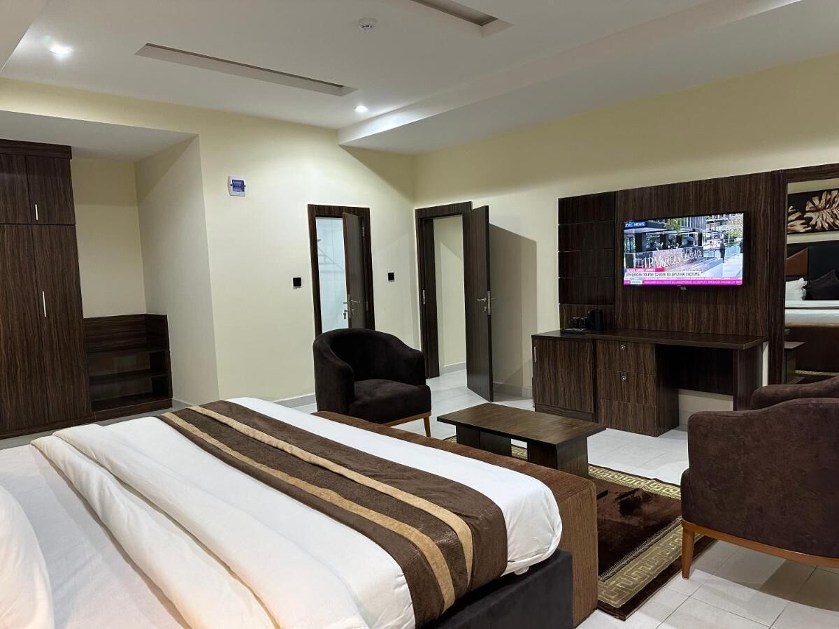 A hotel room with a large bed, a TV, a desk, and a chair.