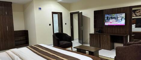 A hotel room with a large bed, a TV, a desk, and a chair.