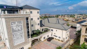 A Vinpy Hotels building with a prominent logo, multiple floors, and a parking area. - Vimpy Hotel Uyo (Uyo)