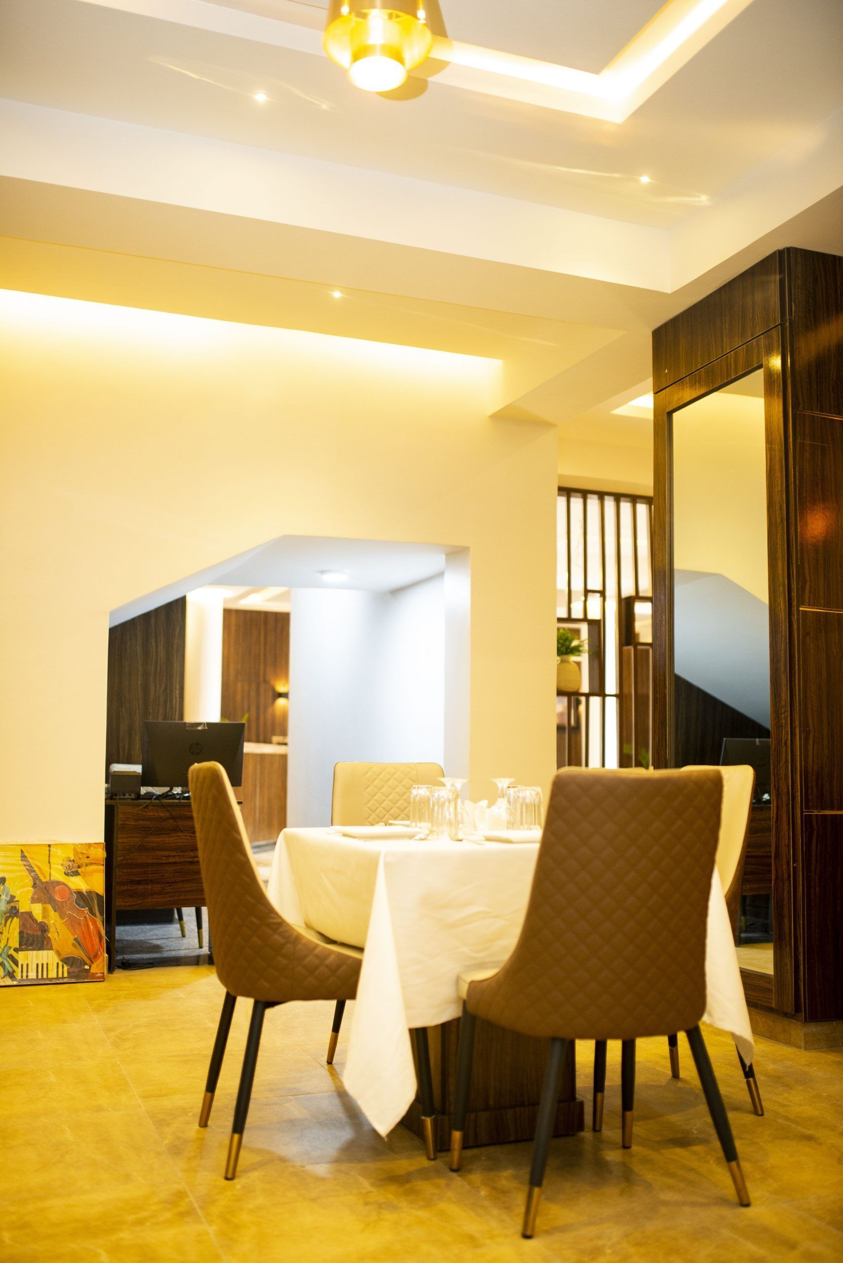 A dining area with a round table, four chairs, and a laptop on a desk.