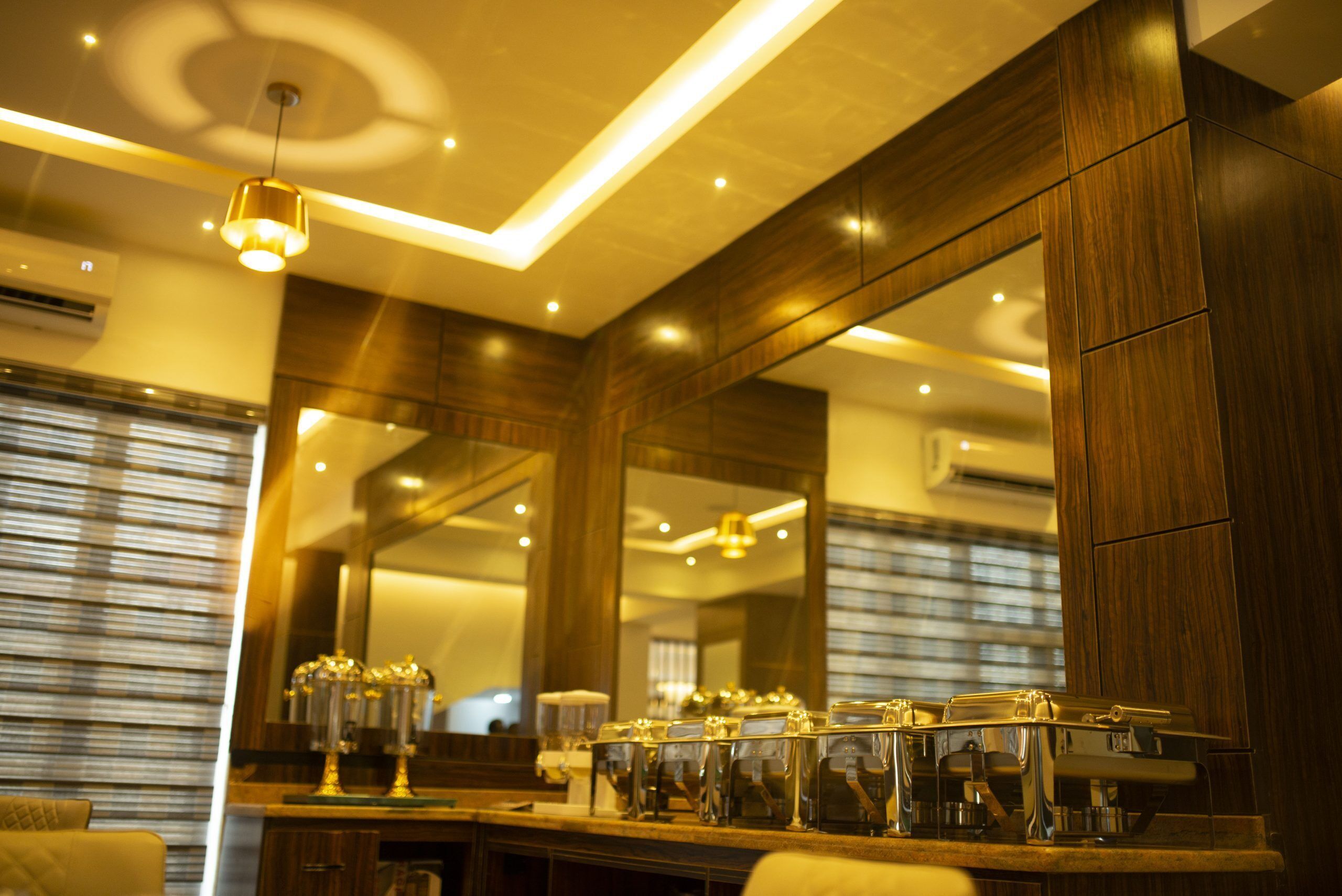 A modern bathroom with a large mirror, wooden cabinets, and a countertop with coffee machines.