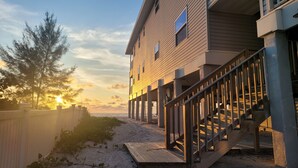 Un edificio de madera con terraza y escaleras que dan a una playa.