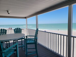 A covered outdoor area with a table and chairs, overlooking a beach with people and a person fishing. - Beachfront Bliss: Quiet Sand Beach, Stargazing Nights – Be One with the Beach (Englewood)