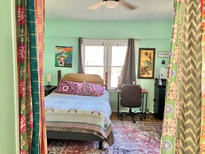 Un dormitorio con cama, escritorio, silla, ventana y una barra de café.