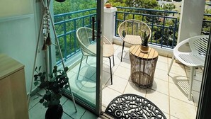 A balcony with two wicker chairs, a small table, and a potted plant.