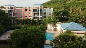 A multi-story hotel with balconies, a swimming pool, and lush greenery.