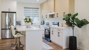 Een moderne keuken met een centraal eiland, roestvrijstalen apparatuur en houten kastjes.