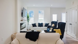 Een moderne woonkamer met een witte bank, een blauwe fauteuil en een salontafel.