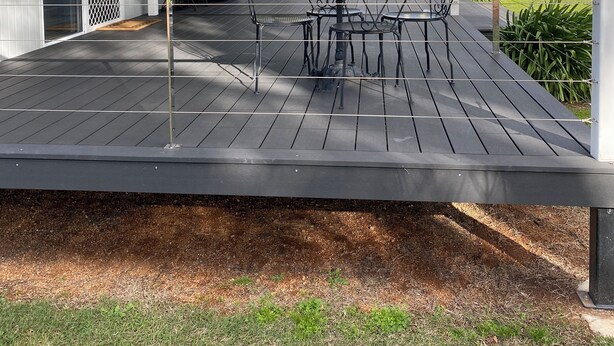 Une terrasse extérieure couverte, dotée d’une table et de chaises, d’un barbecue et offrant une vue sur le paysage environnant.