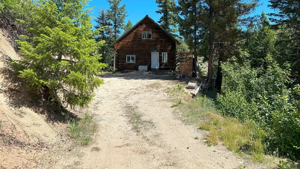 A rustic log cabin with a dirt path leading to the entrance, surrounded by dense trees and greenery. - Off Grid Cabin With WIFI! Surrounded by hiking trails, beautiful scenery (Lowman)