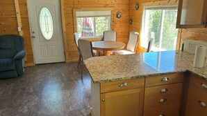A wooden cabin interior with a dining area, kitchen, and a blue chair. - Off Grid Cabin With WIFI! Surrounded by hiking trails, beautiful scenery (Lowman)
