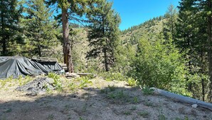 A campsite with tents, a wooden deck, and a forested hillside in the background. - Off Grid Cabin With WIFI! Surrounded by hiking trails, beautiful scenery (Lowman)