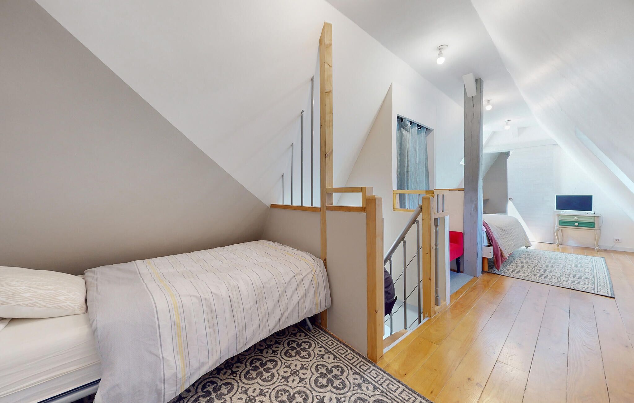Une chambre à coucher aménagée dans un espace en hauteur, avec un lit superposé, un bureau et une fenêtre.
