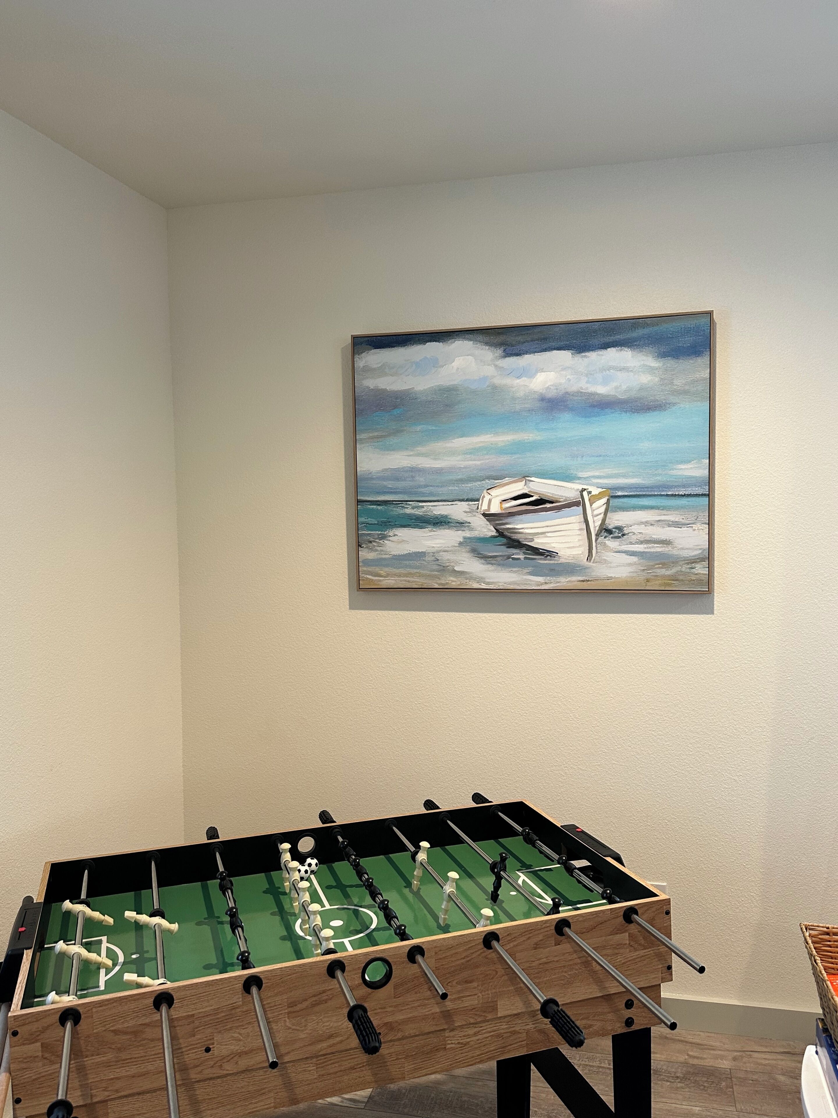 Ett fotbollsspelbord i ett rum med en målning av en båt på väggen.