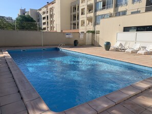 A rectangular swimming pool with clear blue water, surrounded by a tiled deck.