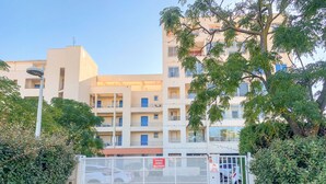 Ingresso chiuso da cancello per un edificio residenziale a più piani con balconi e cielo sereno.