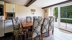 A dining area with a wooden table and patterned chairs, a microwave, and a refrigerator. - U sjezdovky by Interhome (Smržovka)