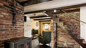 A rustic interior with exposed brick walls, a wooden staircase, a vintage stove, and a cozy seating area. - U sjezdovky by Interhome (Smržovka)