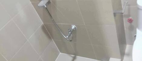 Un espace douche équipé d’un pommeau de douche à main et d’un robinet fixé au mur.