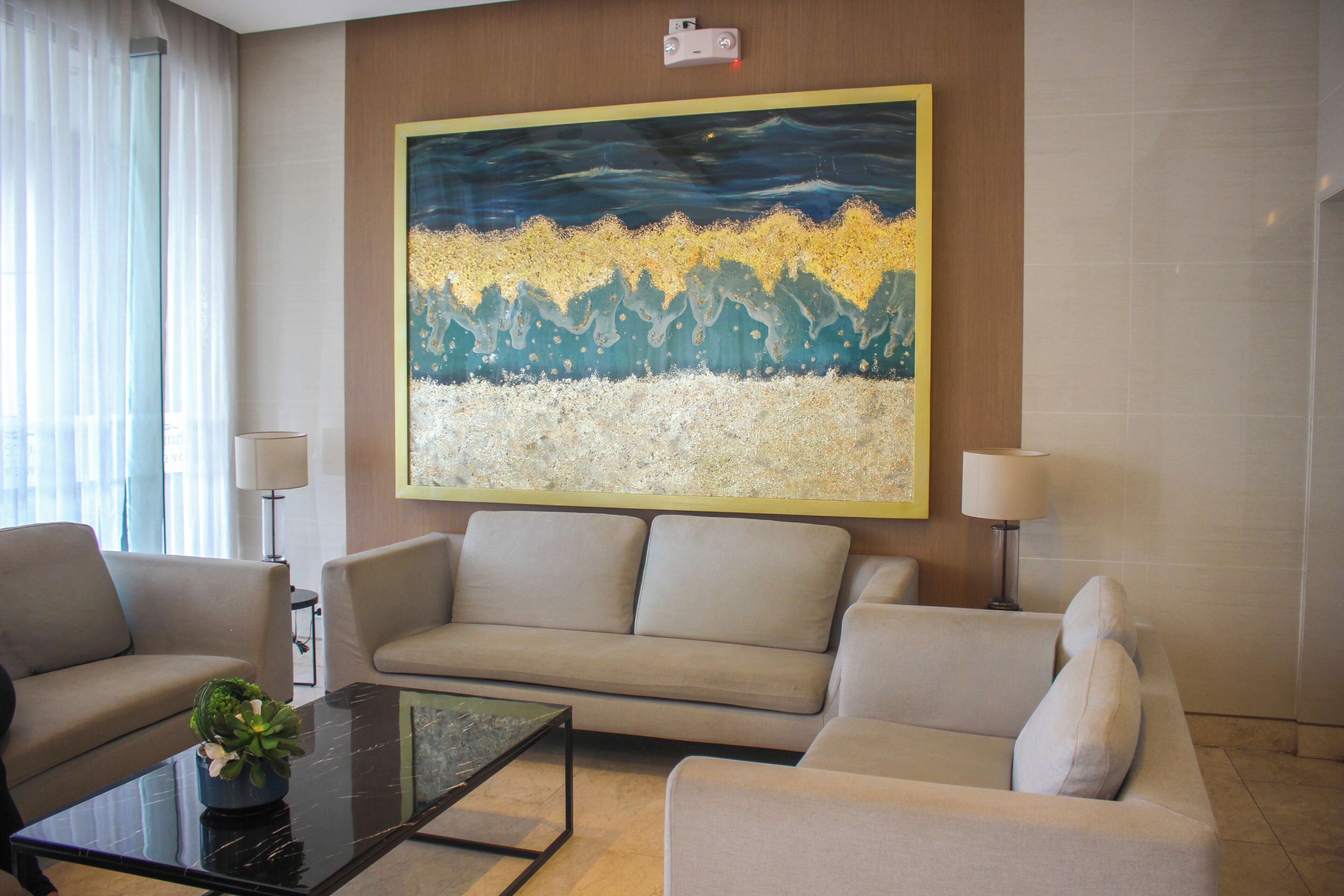 A modern living room with a sofa, a coffee table, and a large abstract painting on the wall.