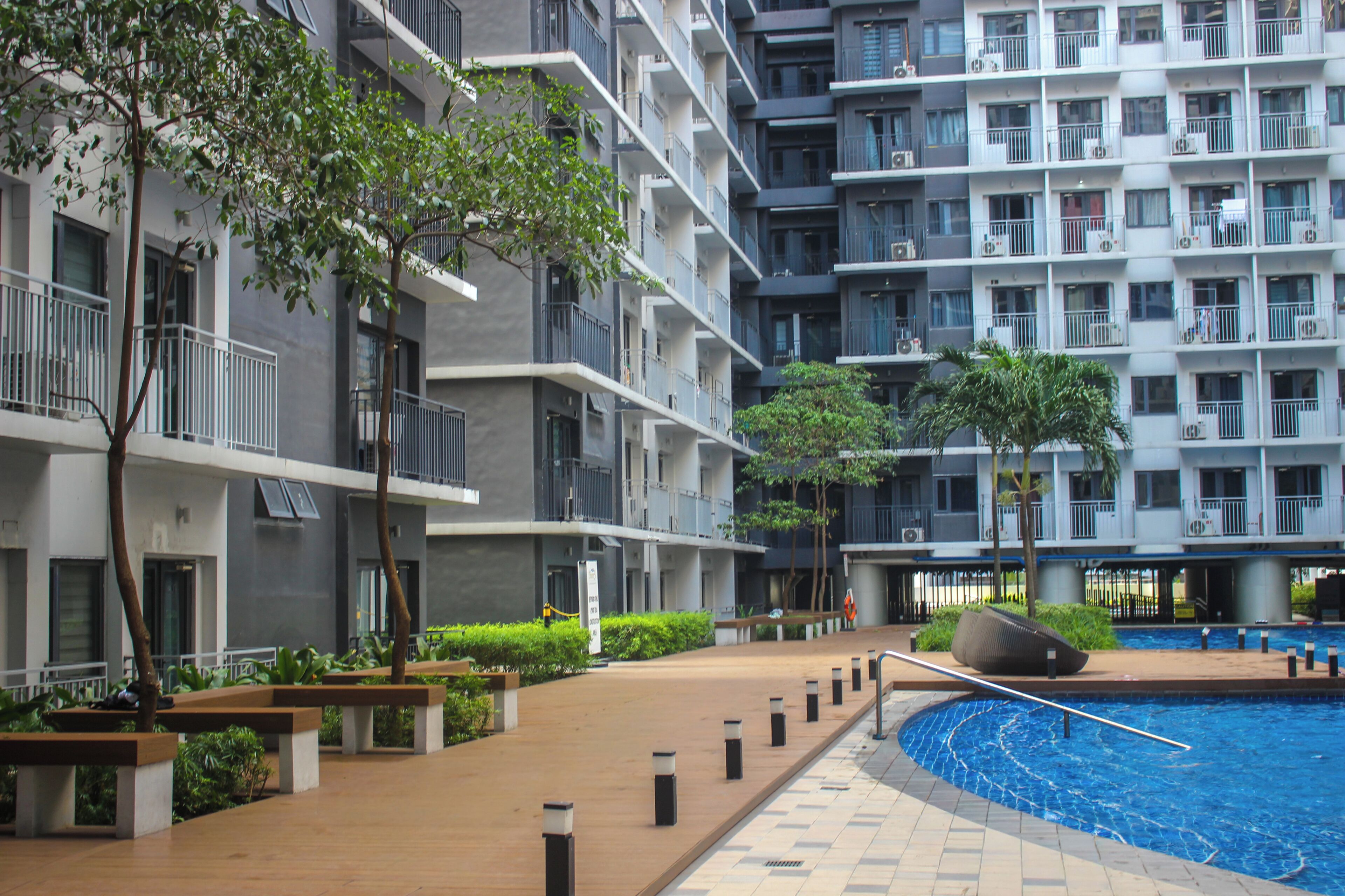 A modern apartment building with balconies, a swimming pool, and outdoor seating areas.