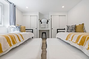 A bedroom with two beds, white walls, and a small desk with a mirror. - Arvada Olde Town Oasis Accomodates 24 People (Arvada)