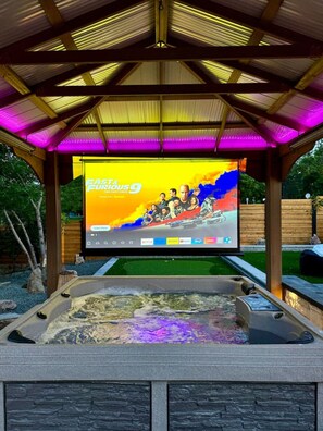 Un espace extérieur abrité doté d’un grand écran diffusant le film « Fast & Furious 9 » et d’un jacuzzi.