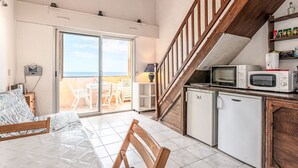 A compact kitchen with a microwave, a small refrigerator, and a dining area with a table and chairs. - Bella Vista by Interhome (Algajola)