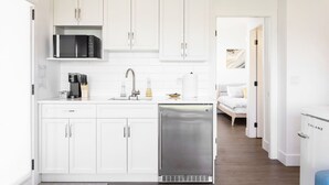 Una cocina moderna con armarios blancos, un refrigerador de acero inoxidable y un microondas.