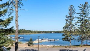A lakeside view with chairs and a fire pit, boats docked, and a clear sky.