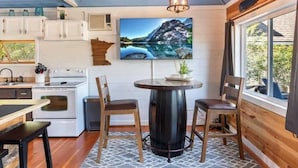 A kitchen with white cabinets, a stove, and a dining area with a round table and chairs.